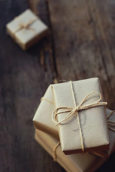 Simple eco friendly gift boxes package wrap with brown paper on wooden table with garden background, green present concept, copy space, earth tone color