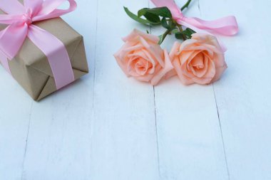 Pembe kurdele ve kahverengi hediye kutusu beyaz ahşap masa arka planda, kopya alanı tarafından bağlı güzel yumuşak turuncu pembe renk gül