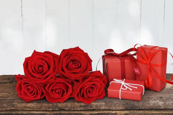 Lovely blooming red color rose flower and elegant gift box on wood table background decorated with mini red heart figure, sweet valentine present concept, copy space