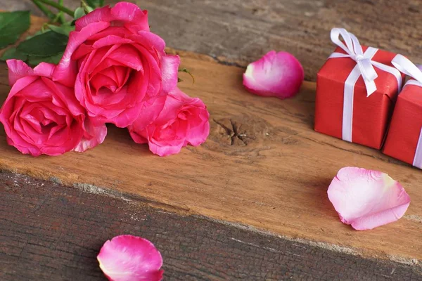 Elegant pink rose, gift box decorated with petals and card with natural soft light on wood background, beautiful valentine\'s day background concept, copy space
