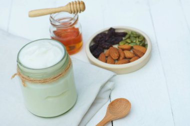 Beyaz kase, tatlım, tahıl, Kuru üzüm ve beyaz ahşap masa arka plan, kopya alanı üzerinde tahta kaşık sade yoğurt