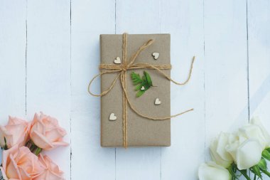 Kahverengi Eko dostu hediye kutusu ile yumuşak pembe dekore edilmiş ve beyaz gül Beyaz ahşap masa, tatlı güzel hediyesi Sevgililer kavramı, kopya alanı