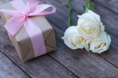 Pembe kurdele ve kahverengi hediye kutusu ahşap masa arka plan üzerinde bağlı güzel yumuşak turuncu beyaz renk gül, tatlı Sevgililer sunmak kavram, kopya alanı