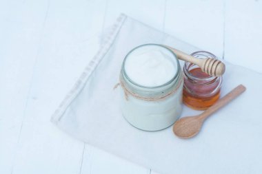 Beyaz kase, tatlım, tahıl, Kuru üzüm ve beyaz ahşap masa arka plan, kopya alanı üzerinde tahta kaşık sade yoğurt