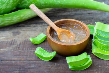 Taze aloe vera bitki, kök dilimleri ve jel ahşap arka plan, deri tedavisi kavramı, kopya alanı