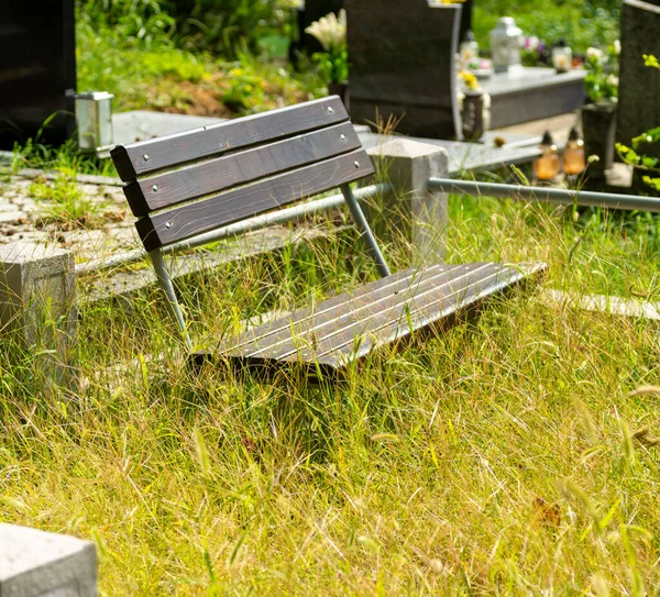 墓园里的草丛里 长着金属制的木板凳 安安静静地坐在墓旁 — 图库照片