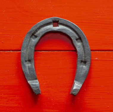 Kırmızı ahşap arka planda eski paslı at nalı.