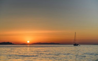 Tropik adanın okyanus maliyetinde güzel bir gün batımı. Önünde tek bir tekne var. Büyülü ve harika bir gün batımı. Duygusal an..