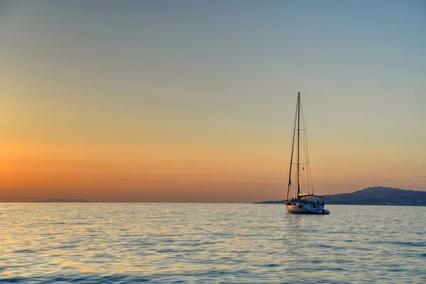 Wonderful sunset time on sea cost of greek island with beautiful yacht in foreground.