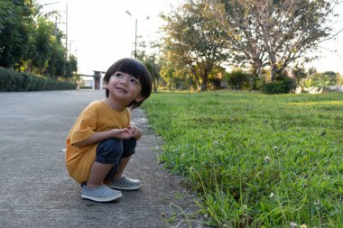 parkta çim çim oynayan mutlu sevimli çocuk