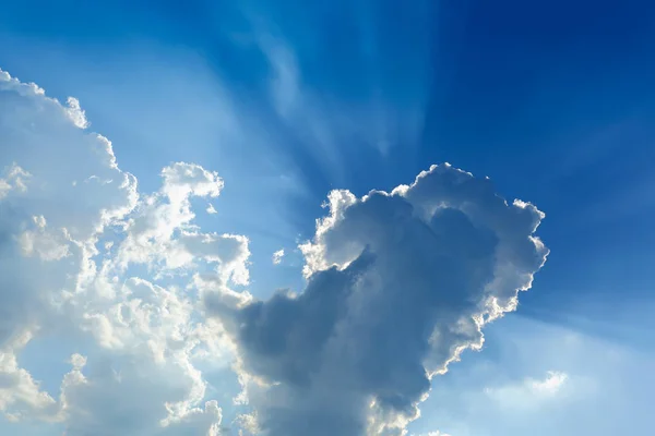 sun rays through cloud above clear blue sky