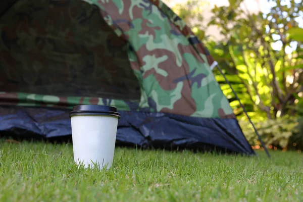 Гарячий кавовий напій, біла одноразова чашка на зеленому газоні — стокове фото