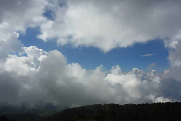 Flauschige Nebelwolke am Himmel über dem immergrünen Berg — Stockfoto
