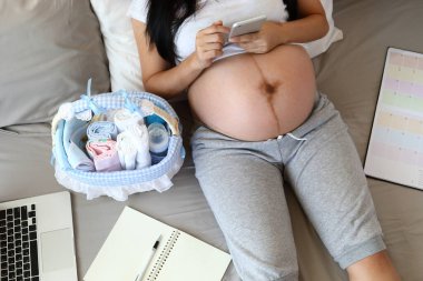 Yeni doğan anne annelik hazırlıkları bebek sevgisi, bebek bezi, sepetteki süt şişesi, dizüstü bilgisayar, defter çizelgesi...