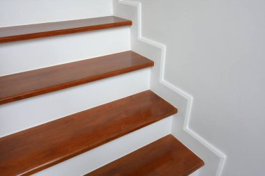 Kahverengi ahşap merdiven ve beyaz duvar.