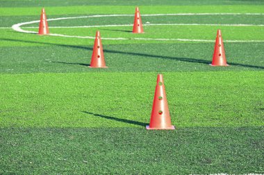 Yapay yeşil çimen futbol sahası ve turuncu eğitim konileri