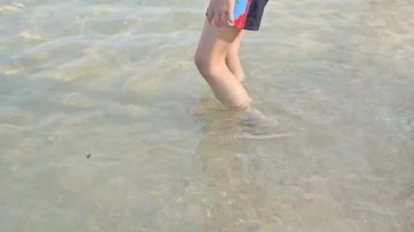 Ağır çekim sahnesi, çıplak ayaklı çocuk yaz deniz yolculuğunun kumsalında oynamaktan mutlu.