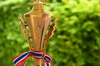 Yeşil ağaç zemininde Tayland ve kurdeleli güzel altın kupa