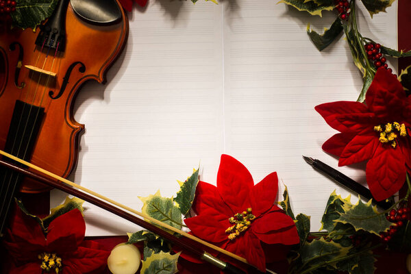 Violin and open music manuscript on the red background. Christmas concept. Copy space