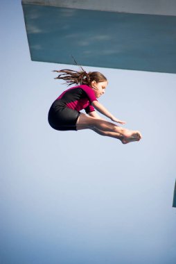 Pike dalışı. Kafkas kadın 8 yaşında, neopren kısa sörf kıyafeti giymiş 5 mether dalış platformundan dalış yapıyor. Yaz, spor ve eğlence konsepti.