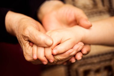 Büyük anne torununun elini tutuyor, yakın plan fotoğrafı. Aile bakımı, yaşlılar ve jenerasyon kavramı