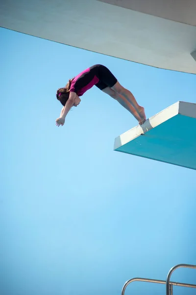 穿着新婚短袖冲浪湿衣的小高加索女8岁女孩从5米跳水平台上跳水 体育和娱乐概念 — 图库照片