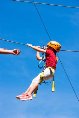 5 metre yükseklikteki bir çocuk parkında ip ipi kullanan 7 yaşındaki küçük cesur beyaz kız. Süresiz bir adam yardım eli uzatır..