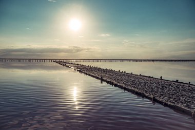 Pembe tuz gölünde gün batımı, pembe tuz çıkarmak için eski bir maden. Tuzla kaplanmış tahta çiviler..