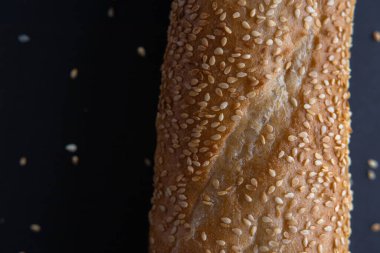 Koyu bir arka planda susam tohumlu çıtır taze Fransız ekmeği.