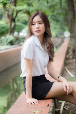 Taylandlı yetişkin öğrenci üniforması portresi. Güzel kız rahatla ve gülümse.