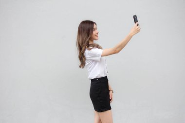 Taylandlı yetişkin öğrenci üniformasının portresi. Güzel kız akıllı telefonuyla selfie çekiyor.