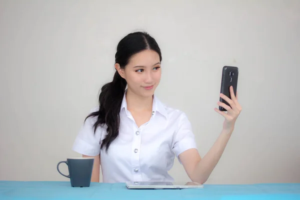 タイのポートレート大人学生大学制服美しいです女の子使用して彼女のスマートフォンSelfie — ストック写真