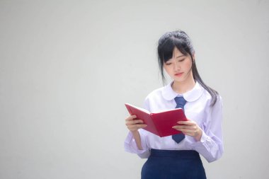Asya Taylandlı lise öğrencisi üniforması. Güzel kız bir kitap okumuş.