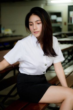 Taylandlı yetişkin öğrenci üniforması portresi. Güzel kız rahatla ve gülümse.