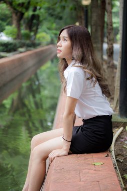 Taylandlı yetişkin öğrenci üniforması portresi. Güzel kız rahatla ve gülümse.