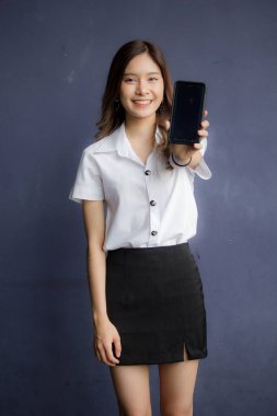 Taylandlı yetişkin öğrenci üniformasının portresi. Akıllı telefonunu kullanan güzel bir kız.