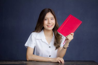 Taylandlı yetişkin öğrenci üniforması portresi. Güzel kız kırmızı kitabı okudu.