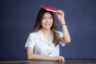 Taylandlı yetişkin öğrenci üniforması portresi. Güzel kız kırmızı kitabı okudu.