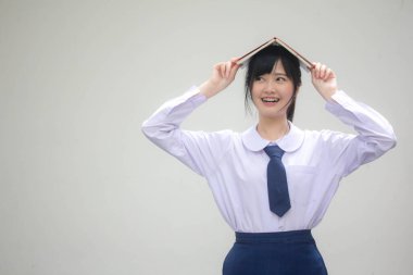 Asya Taylandlı lise öğrencisi üniforması. Güzel kız bir kitap okumuş.