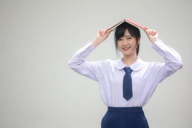 Asya Taylandlı lise öğrencisi üniforması. Güzel kız bir kitap okumuş.