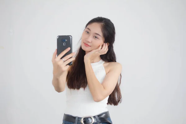 タイの肖像中国大人美しいです女の子ホワイトシャツブルージーンズ使用して彼女のスマートフォンSelfie — ストック写真