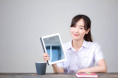 Portrait of thai high school student uniform beautiful girl using her tablet