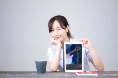 Portrait of thai high school student uniform beautiful girl using her tablet