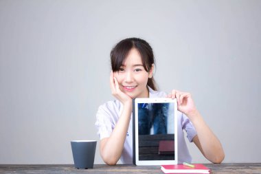 Portrait of thai high school student uniform beautiful girl using her tablet