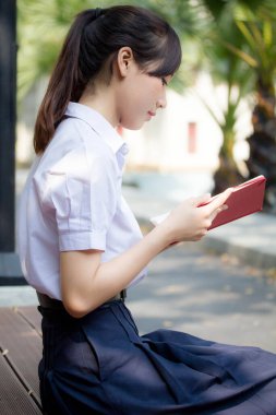 Asya Taylandlı lise öğrencisi üniforması. Güzel kız bir kitap okumuş.