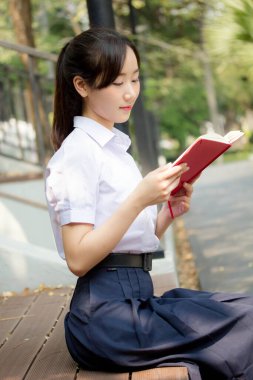 Asya Taylandlı lise öğrencisi üniforması. Güzel kız bir kitap okumuş.
