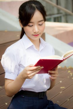 Asya Taylandlı lise öğrencisi üniforması. Güzel kız bir kitap okumuş.