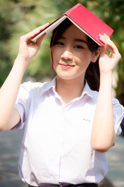 Asya Taylandlı lise öğrencisi üniforması. Güzel kız bir kitap okumuş.