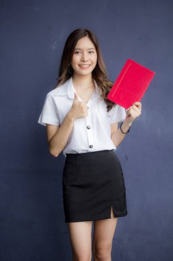 Taylandlı yetişkin öğrenci üniforması portresi. Güzel kız kırmızı kitabı okudu.