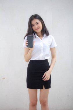 Taylandlı yetişkin öğrenci üniforması portresi. Güzel kız akıllı telefonunu göster.